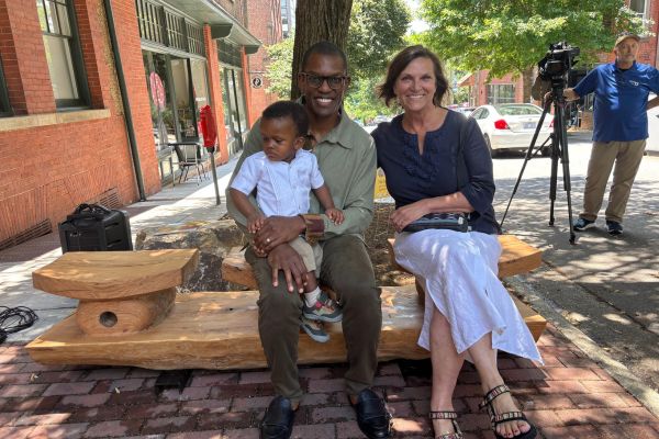 A family seated on the new white oak bench at the YMI Cultural Center